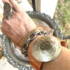 a person's hand with a metal bracelet on it and a coin in the middle