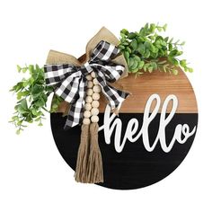 a wooden sign with the word hello on it and some greenery in front of it