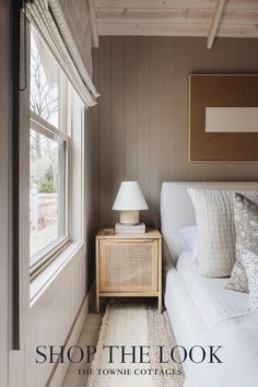 a white couch sitting next to a window in a room with wood paneled walls