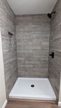 a walk in shower sitting next to a wooden floor