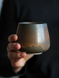 a person holding a gray cup in their left hand and black shirt on the other