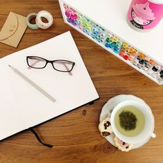 a cup of green tea next to a pair of glasses on top of a table