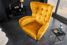 a yellow chair sitting on top of a hard wood floor next to a black table