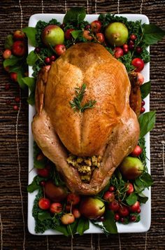 a turkey on a platter with apples and other holiday foods