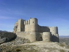 an old castle sits on top of a rocky hill in the middle of the desert