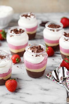 small desserts with strawberries and chocolate on a marble countertop next to utensils