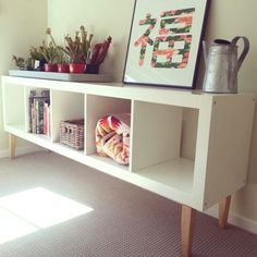 a white shelf with some books and plants on it