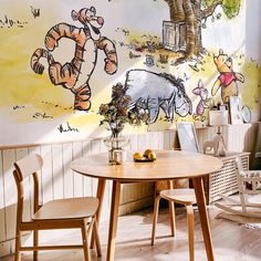 winnie the pooh wall mural in a children's room with wooden chairs and table