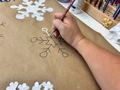 someone is making snowflakes out of paper with scissors and crayons on the table