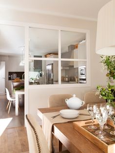 a dining room table with place settings and flowers in vases on the top shelf