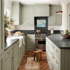 a kitchen with green cabinets and black counter tops, along with an area rug on the floor