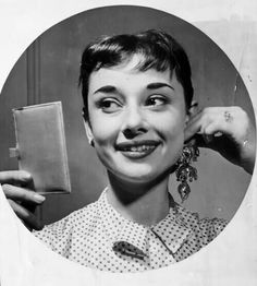 an old black and white photo of a woman holding a small book in front of her face