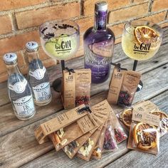 several bottles and bags of alcohol sitting on a wooden table next to some wine glasses