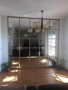 a living room with a couch, chandelier and large glass window in it