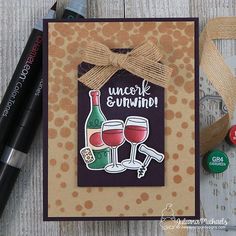 a card with some wine glasses and a bottle on it, next to two markers