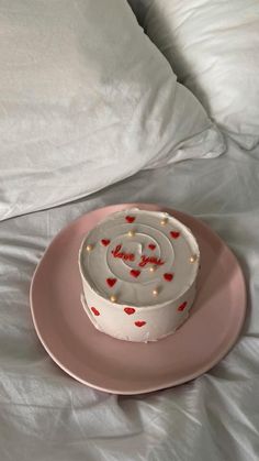 a white cake on a pink plate with red hearts