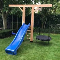 a wooden swing set with a blue slide and black trampoline in the back yard