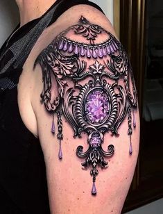 a woman's arm with an intricate tattoo design and purple jewels on the side