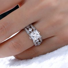 a woman's hand with a diamond ring on top of her finger and the other hand holding an engagement ring