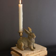 a candle holder with a rabbit figurine sitting on top of it next to a book