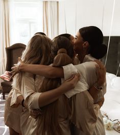 three women hugging each other in front of a mirror