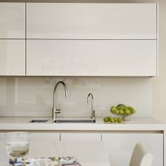 a kitchen with white cabinets and green fruit on the counter