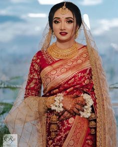 a woman in a red and gold bridal outfit with her hands on her hips