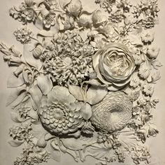 an intricately designed wall with flowers and leaves on it's side, in white