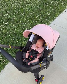 a baby in a stroller with a pink umbrella over it's head on the sidewalk