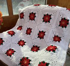 a white crocheted blanket with poinsettis on it sitting in front of a window