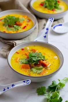 two white bowls filled with soup and garnished with cilantro