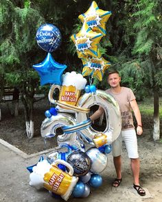 a man standing next to a giant balloon shaped like a number 50 with beer and balloons