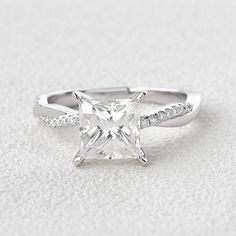 a white gold ring with a princess cut diamond and pave set diamonds on the band