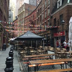 tables and benches are lined up on the sidewalk in front of buildings with bunting