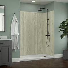 a bathroom with green walls and wood floors, including a shower stall that has an open door to the bathtub