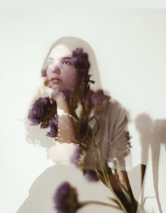 a woman with long hair holding a flower in front of her face