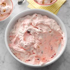 a bowl filled with whipped cream next to two spoons on top of a table