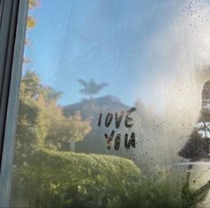 the words love you are written on a window sill in front of some bushes