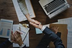 two people shaking hands over papers on a wooden table with the words oracle above them