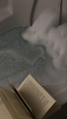 an open book sitting on top of a bathtub filled with water