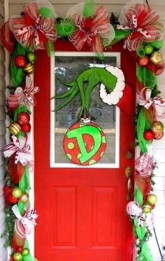 a red door decorated with christmas decorations and wreaths on the front porch for an elf's party