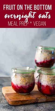 three jars filled with fruit on the bottom and overnight oats in them, sitting on a cutting board