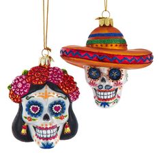 two colorful skulls wearing sombrero hats hanging from strings on a white background with one skull in the foreground