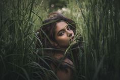 a woman standing in tall grass looking at the camera