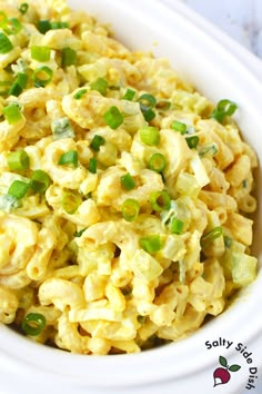 a white bowl filled with macaroni salad on top of a wooden table