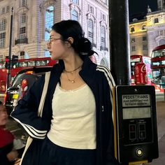 a woman standing next to a pole on a city street