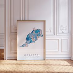 a framed map of morocco on a wall in a room with white walls and parquet flooring