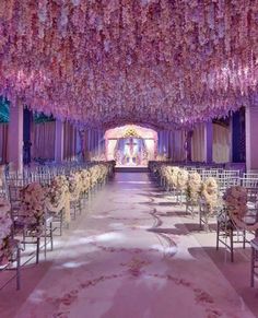 the aisle is lined with white and pink floral arrangements hanging from the ceiling, along with rows of chairs