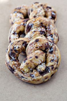 several donuts covered in powdered sugar and raisins on a brown surface