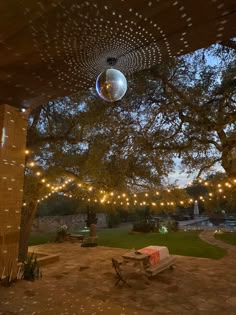 a disco ball hanging from the ceiling in a park area with benches and lights around it